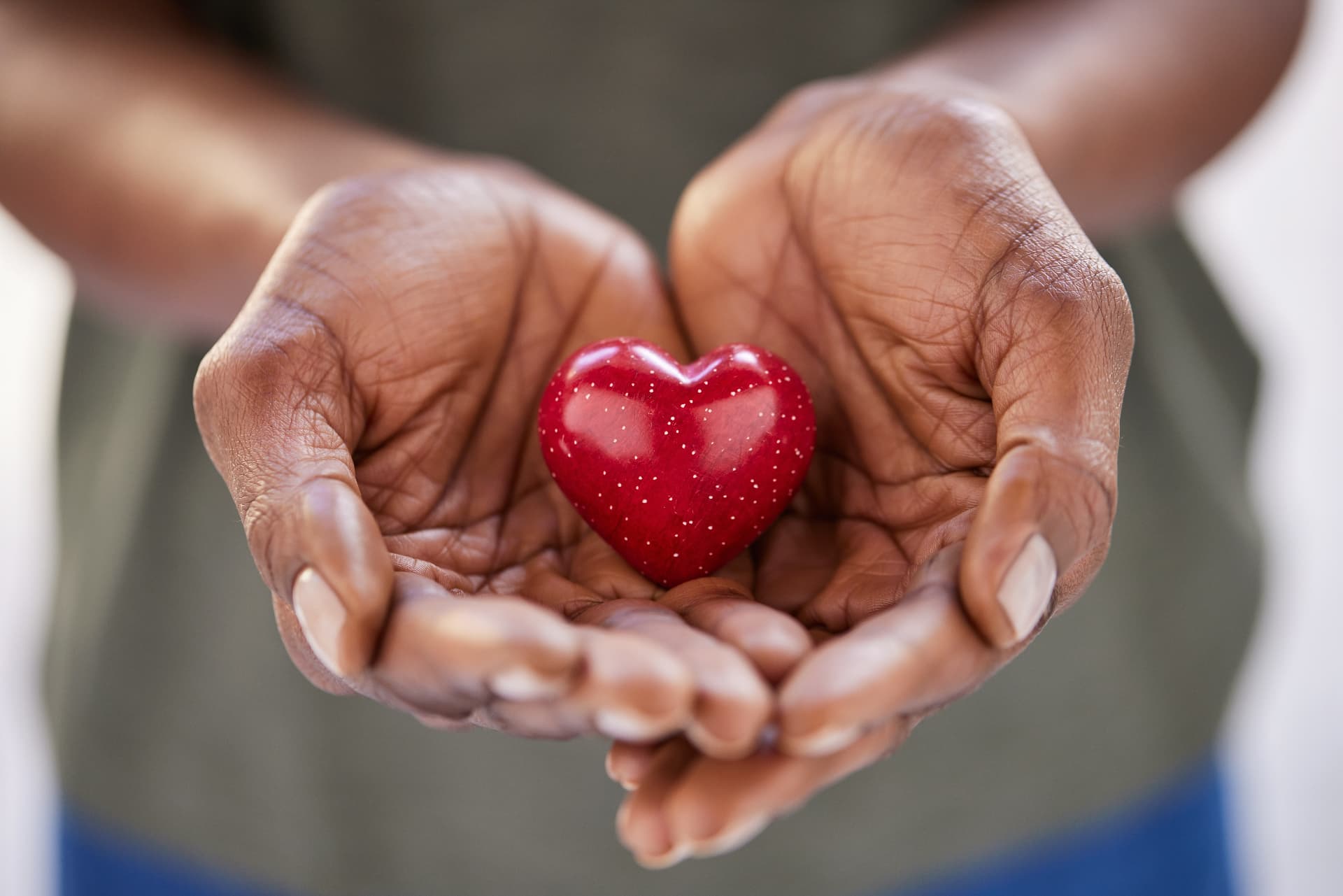 Hands gently holding a small red heart