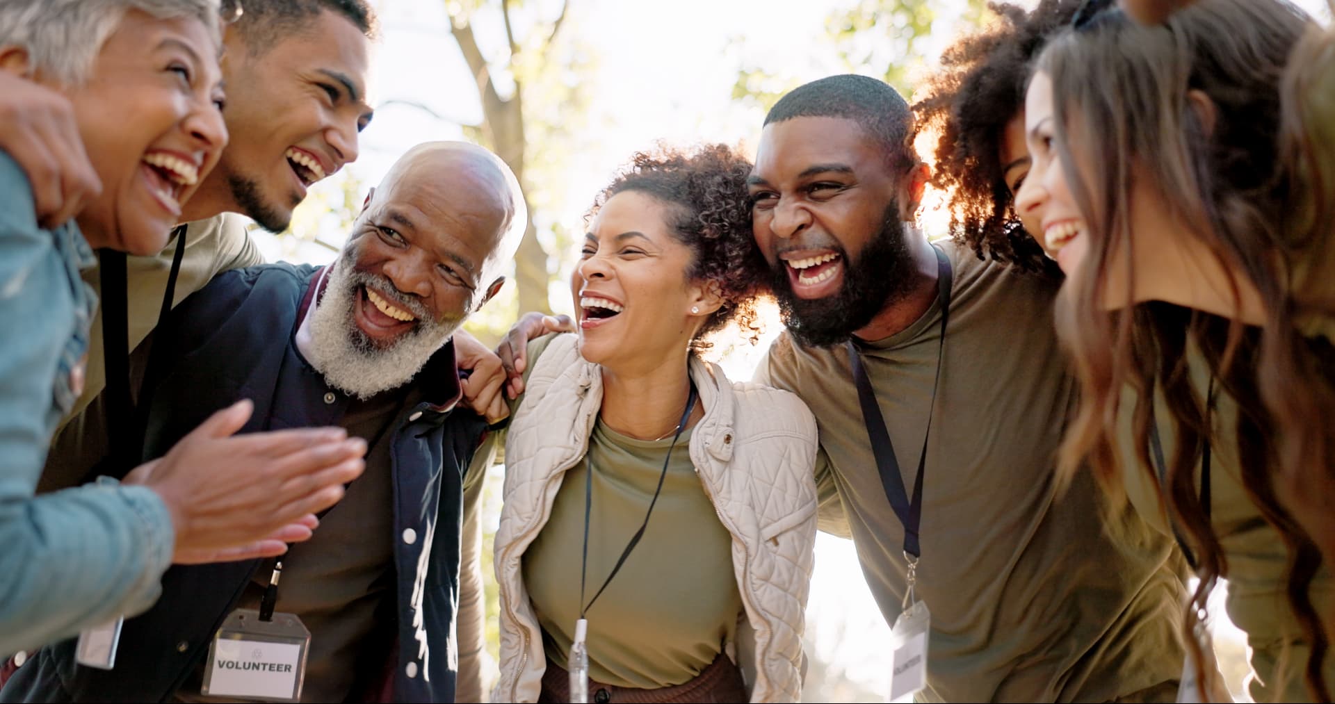 A diverse group of volunteers laughing together outdoors